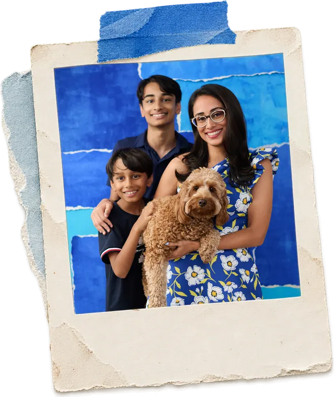 Zainab with her two sons and the family dog against a blue torn-paper backdrop.