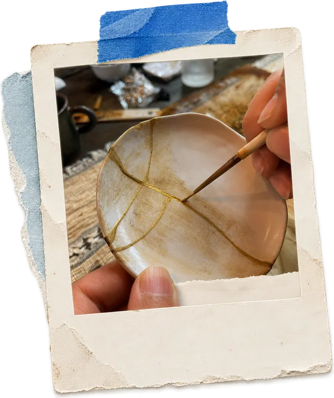 A broken bowl being repaired with gold in the kintsugi tradition.